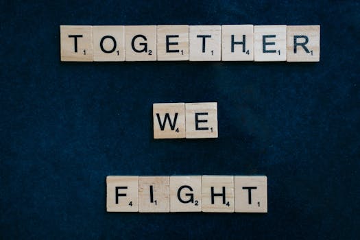 Inspirational message with Scrabble tiles spelling 'Together We Fight' on a dark background.